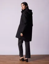 Gabardina negra impermeable con capucha desmontable, cierre central con cremallera y botones a presión, bolsillos delanteros y forro interno.