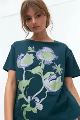 Remera lila de algodón con estampado de flores en tonos naranja y rosa.