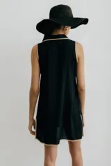 Vestido corto negro con cuello camisero, sin mangas, abotonado al frente y con aberturas laterales.