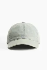 Gorra de denim celeste con ojales bordados en la parte superior, trabilla ajustable con hebilla de metal en la parte trasera y cinta antitranspirante de algodón.