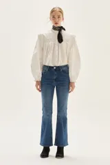 Jean de tiro medio, color azul medio, con silueta ligeramente acampanada desde la rodilla.