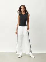 Pantalón blanco de corte ancho con una fina línea negra vertical en los laterales.
