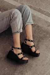 Sandalias negras de plataforma con tiras de gamuza y esferas doradas decorativas.