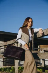 Bolso tipo tote de cuero negro con textura tipo piel de cocodrilo, doble asa de mano y cierre superior con cremallera.