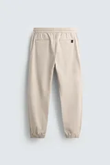 Pantalón jogger negro de corte slim fit, confeccionado en tejido de algodón con cintura elástica ajustable con cordón, bolsillos frontales y traseros de vivo, y bajo con puño elástico.