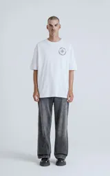 Remera blanca de algodón premium con cuello redondo, mangas cortas y calce oversize. Estampa sublimada con diseño de una figura femenina sosteniendo un salvavidas con la frase "Chill Bitch Trust Karma".