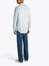 Camisa celeste de manga larga, confeccionada en algodón y lino, con cuello abotonado, cierre con botones, corte regular y logo de Tommy Jeans bordado en el pecho.