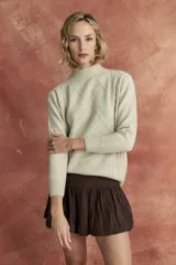Sweater beige de tejido de punto con cuello alto y diseño de rombos en relieve.