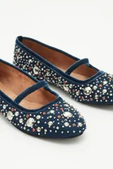Bailarinas planas de gamuza azul marino con tira de terciopelo en el empeine. El cuerpo del zapato está completamente cubierto con apliques y bordados de perlas y cristales en tonos blancos y dorados.