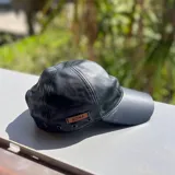 Gorra de cuero color dorado con etiqueta de cuero marrón con el logo de la marca "Bona".