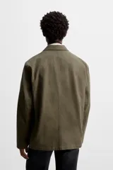 Blazer color verde oliva de algodón con efecto lavado, corte relaxed fit, cuello con solapas de muesca, manga larga y bolsillos frontales de plastrón. Cierre frontal con dos botones.