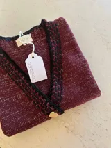 Chaleco tejido a mano con escote en V, bordado con botones, confeccionado en algodón con detalles de lurex. Terminaciones en crochet y bordados hechos a mano con lana merino.