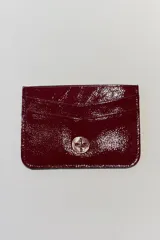 Tarjetero de cuero sintético color borgoña brillante con cierre de botón a presión y múltiples ranuras para tarjetas.