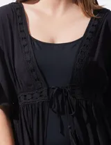 Kaftan blanco largo con mangas cortas y abertura central. Presenta apliques de puntilla en el escote, cintura y ruedo. Se ata en la cintura con un lazo.