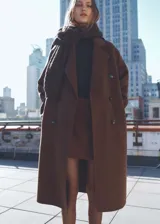 Abrigo marrón de lana con doble botonadura, cuello con solapa de muesca, dos bolsillos laterales, hombros caídos, diseño oversize y largo, con forro interior.