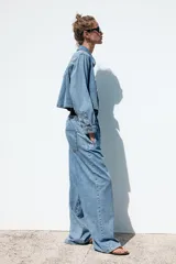 Pantalón de jean azul oscuro, de tiro medio, corte ancho y largo, estilo jogger con cintura elástica ajustable con cordones, bolsillos delanteros de vivo y bolsillos de parche en la espalda.