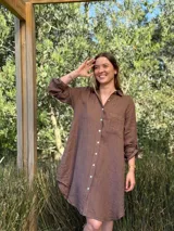 Vestido camisero blanco de lino, con cuello camisero, manga larga con botón para recoger, cierre frontal con botones de nácar, bolsillo en el pecho y diseño asimétrico más largo en la parte trasera.