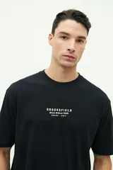 Remera negra de manga corta con estampado en la espalda de un globo terráqueo con el texto "Wild World Tour" y nombres de ciudades.