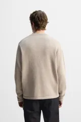 Jersey color beige de punto con cuello redondo y manga larga.