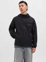 Campera softshell negra con capucha ajustable con cordón, mangas largas con puños de canalé, cierre frontal con cremallera y bolsillos delanteros. Forro sin relleno y costuras cubiertas.