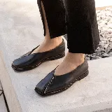 Zapato bajo de cuero negro con punta cuadrada y detalle de cierre en la capellada. Interior forrado en cuero color suela y suela de madera con inclinación de 0,5 cm.