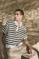 Polo de punto color crema con rayas horizontales verde oscuro, cuello clásico y cierre de botones.