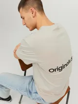 Camiseta color crema de manga corta y cuello redondo con estampado en la espalda que dice 'Originals Studio' y 'Brought to you by Org Dept. Designed in Copenhagen'.