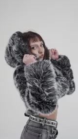 Campera corta con capucha, confeccionada en mezcla de algodón y poliéster, con textura de piel sintética en tonos grises y negros.
