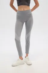 Calza deportiva gris de poliéster, corte ajustado, tiro alto y diseño calado en la parte inferior de las piernas.