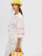 Camisa blanca de broderie de algodón con detalle de galones con transparencias en la parte delantera y mangas, cuello mao con cierre de 4 botones y puños fruncidos.