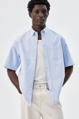 Camisa celeste de algodón Oxford con cuello abotonado, manga corta, bolsillo de parche en el pecho y corte regular.