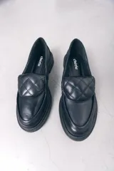 Mocasines negros de cuero con detalle acolchado en la parte superior.