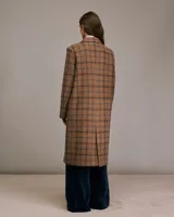 Tapado largo marrón con diseño a cuadros azules, solapas de pico, mangas largas con abertura y botones, bolsillos frontales con tapa y forro interior.