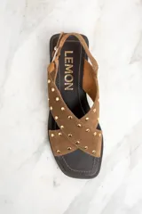 Sandalias bajas de cuero color marrón con tiras cruzadas y tachas doradas.