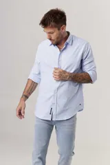 Camisa celeste a rayas verticales blancas, de corte clásico, manga larga y cuello abotonado.