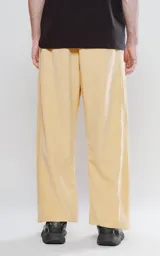 Pantalón de corte sastrero color amarillo claro, de tela suave tipo gamuza, con bolsillos laterales, cintura elástica ajustable y cierre con botón.