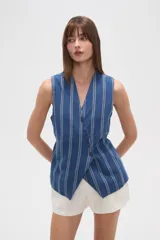 Chaleco sin mangas, color azul con rayas verticales blancas. Diseño cruzado con escote en V profundo y cierre frontal con botones.
