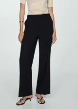 Pantalón largo negro de tejido fluido con diseño wideleg, tiro medio, detalle de pinzas, dos bolsillos laterales y cierre oculto de botón, gancho y cremallera.