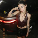 Top negro tipo corset confeccionado en cuero sintético, con escote halter y cierre frontal con ganchos metálicos.