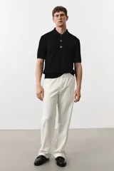 Remera polo negra de manga corta en punto trenzado con cuello clásico, tapeta de botones y bajo recto.
