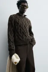Sweater marrón oscuro de punto con estructura de trenzas, cuello redondo, manga larga y corte regular fit.