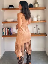 Vestido color beige con breteles finos, corte ajustado y falda con flecos.
