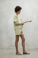 Buzo color verde claro, de corte clásico, con cuello redondo y puños acanalados. Confeccionado en 50% algodón reciclado y 50% algodón orgánico.