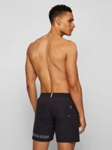 Short de baño negro marca BOSS, modelo Dolphin, con logo repetido en blanco en el ruedo.