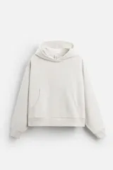 Sudadera color crudo, estilo hoodie, corte boxy, con capucha, manga larga, bolsillo tipo canguro y terminaciones en rib.