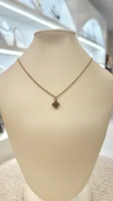 Collar con cadena dorada y dije de amatista en bruto con forma de cruz.