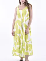 Vestido largo estampado, con tirantes anudados al hombro. El estampado es de formas orgánicas grandes en color verde lima y blanco. El vestido tiene un corte suelto y volados en el ruedo.