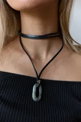 Collar con tiento negro y dije de piedra natural ovalada en tonos grises y azules.