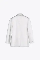 Blazer oversize de satén color blanco, con cuello solapa, escote pico cruzado, manga larga con hombreras, bolsillos de doble vivo y abertura en la espalda. Cierre frontal cruzado con botones forrados.