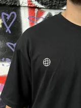 Remera negra oversize con cuello redondo y estampado pequeño en el pecho.